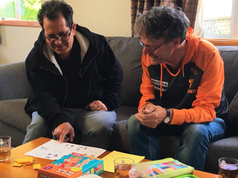 A photo of Martin, a tutor, sitting next to a client who is pointing to a teaching resource