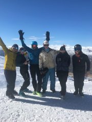 Volunteers on the slopes in their snow gear, lined up together smiling at the camera.