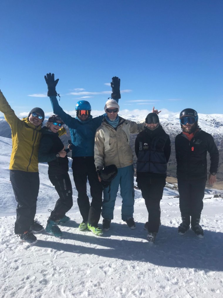 Volunteers on the slopes in their snow gear, lined up together smiling at the camera.