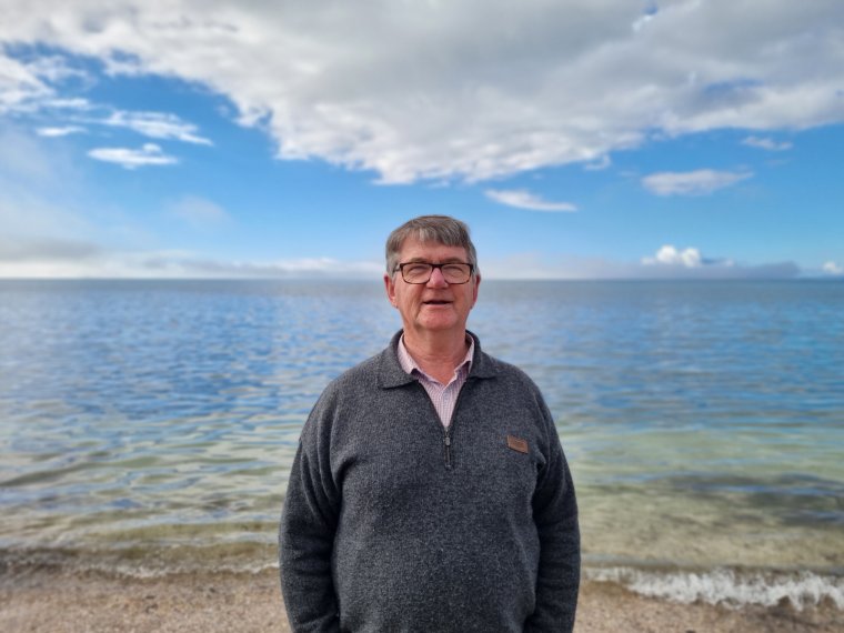 Ian standing on a beach.