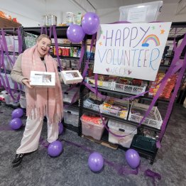 Volunteer standing with a big sign that says Volunteer Week