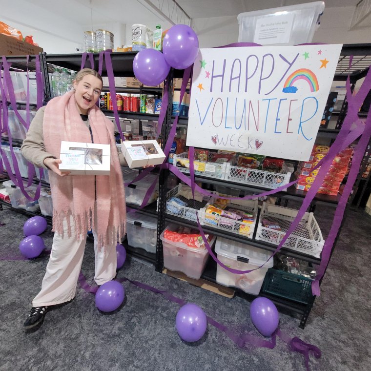 Volunteer standing with a big sign that says Volunteer Week