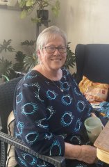 Ann sat in a chair smiling at the camera.