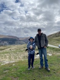 Darren and Jett standing in the countryside smiling at the camera.