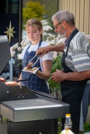 Barry at the BBQ placing a sausage onto a slice of bread.