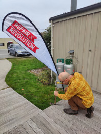 Adrian fixing a garden tool under the repair revolution flag