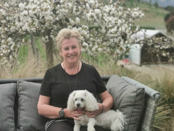 Celia sitting outside with a white fluffy dog on her lap.