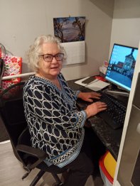Alison sat in a desk chair at a desk, hands on the keyboard, turned smiling at the camera