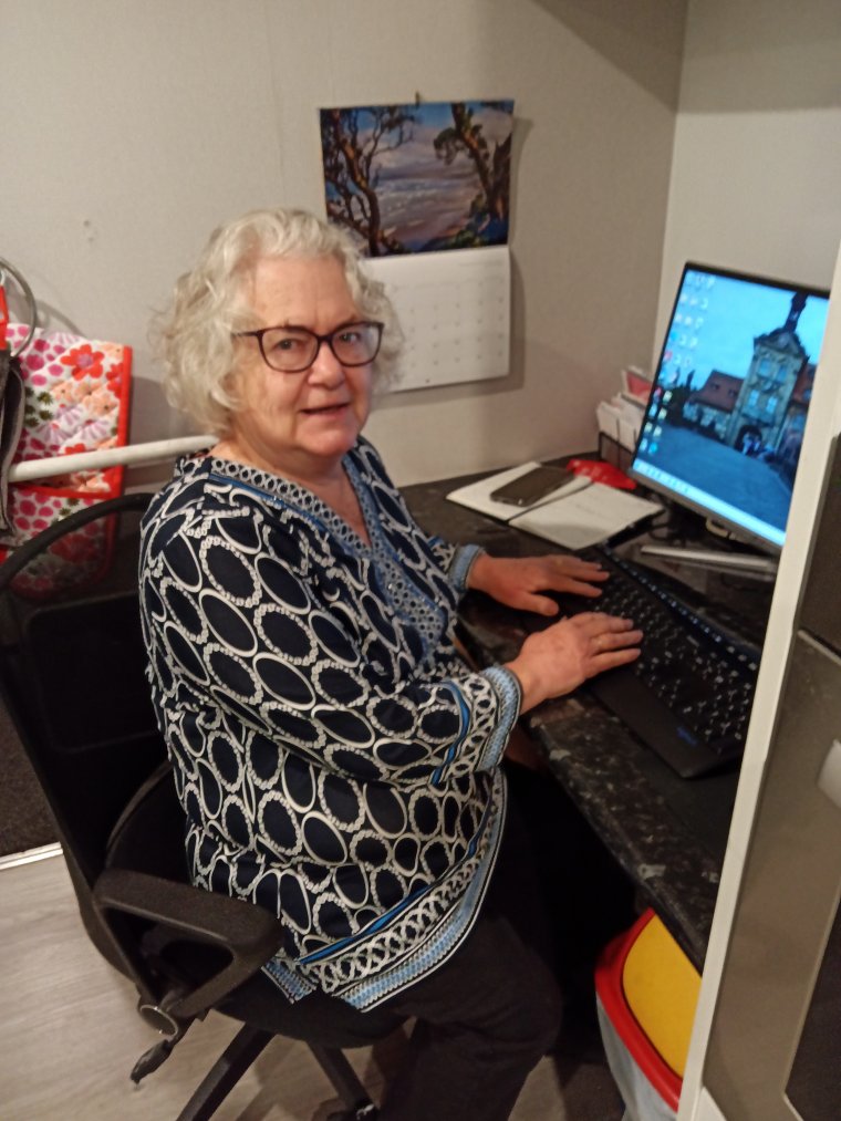 Alison sat in a desk chair at a desk, hands on the keyboard, turned smiling at the camera