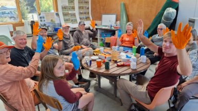 Group of volunteers holdind up their colourful gloved hands and smiling at the camera.