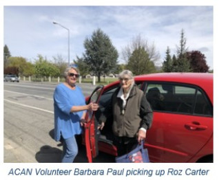 A volunteer and their client standing next to a red car