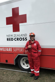Julia wearing Red Cross overalls with a rope over her shoulder, standing in front of a Red Cross Truck