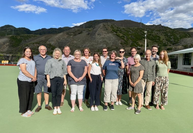 15 people standing on astroturf infront of a mountain