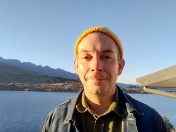 A close-up of Ben's face in front of lakes and mountains