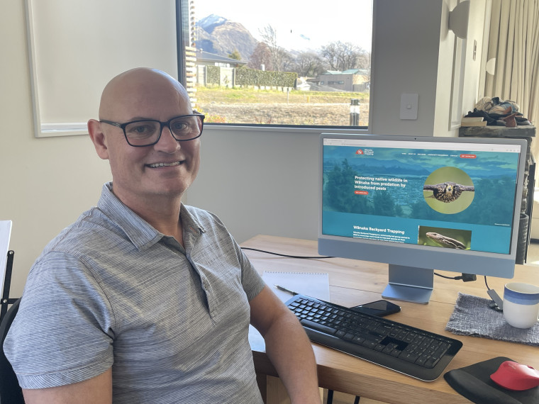 Guy Kennedy sitting at a desk with the Wanaka Backyard Trapping website open on the computer.