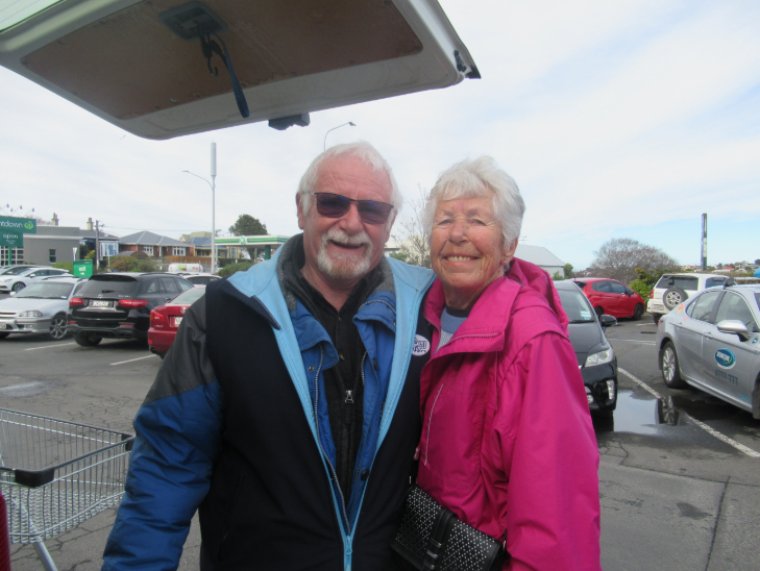 Neil and Nancy standing in a carpark smiling at the camera.